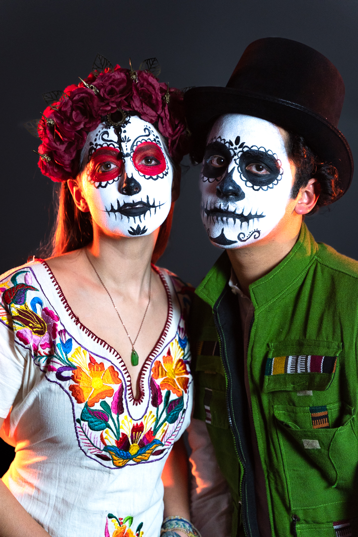 Calavera couple poses wearing attire inspired by the Dia de los Muertos celebrations